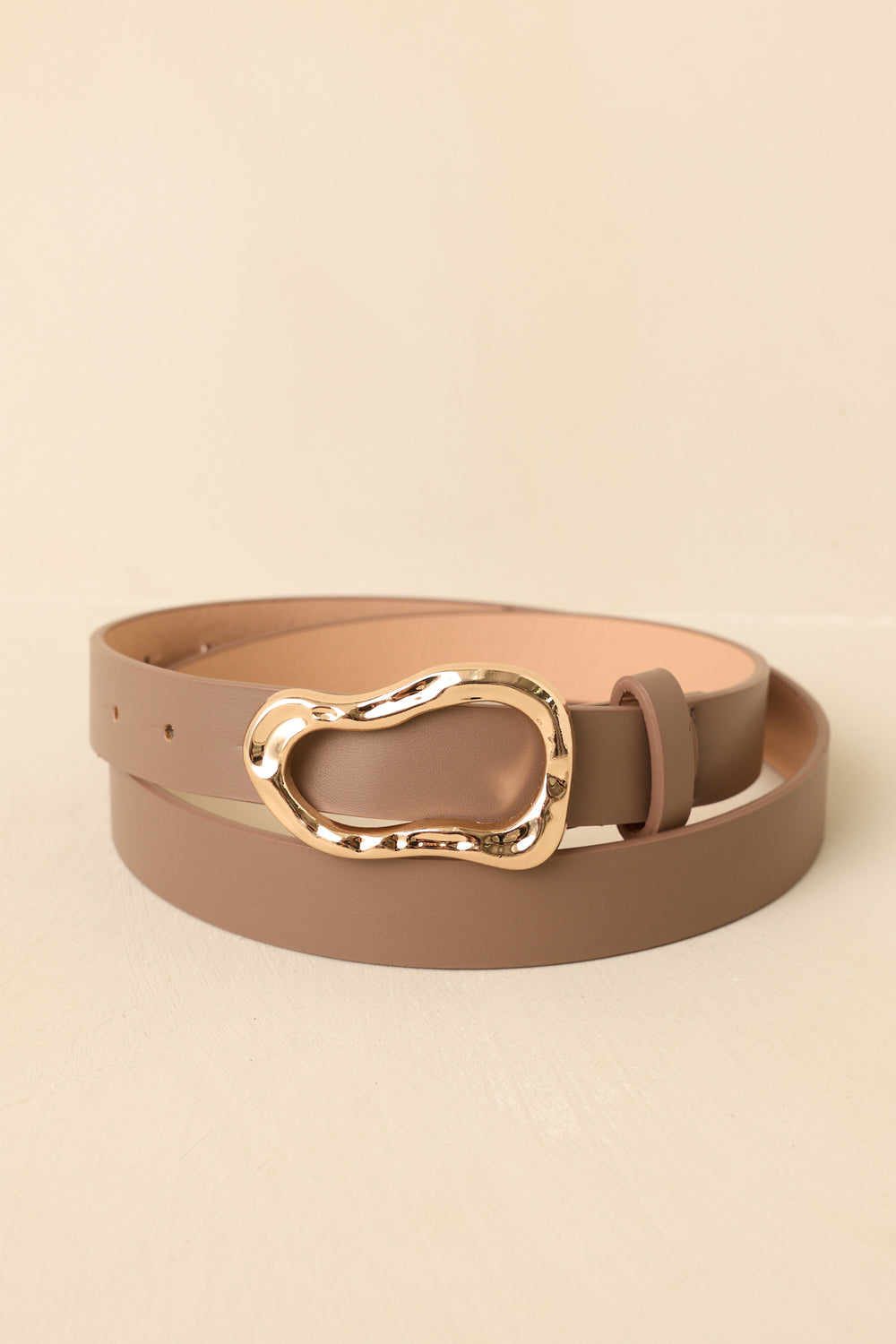 Brown-Belt-With-A-Gold-Buckle-On-A-Beige-Background