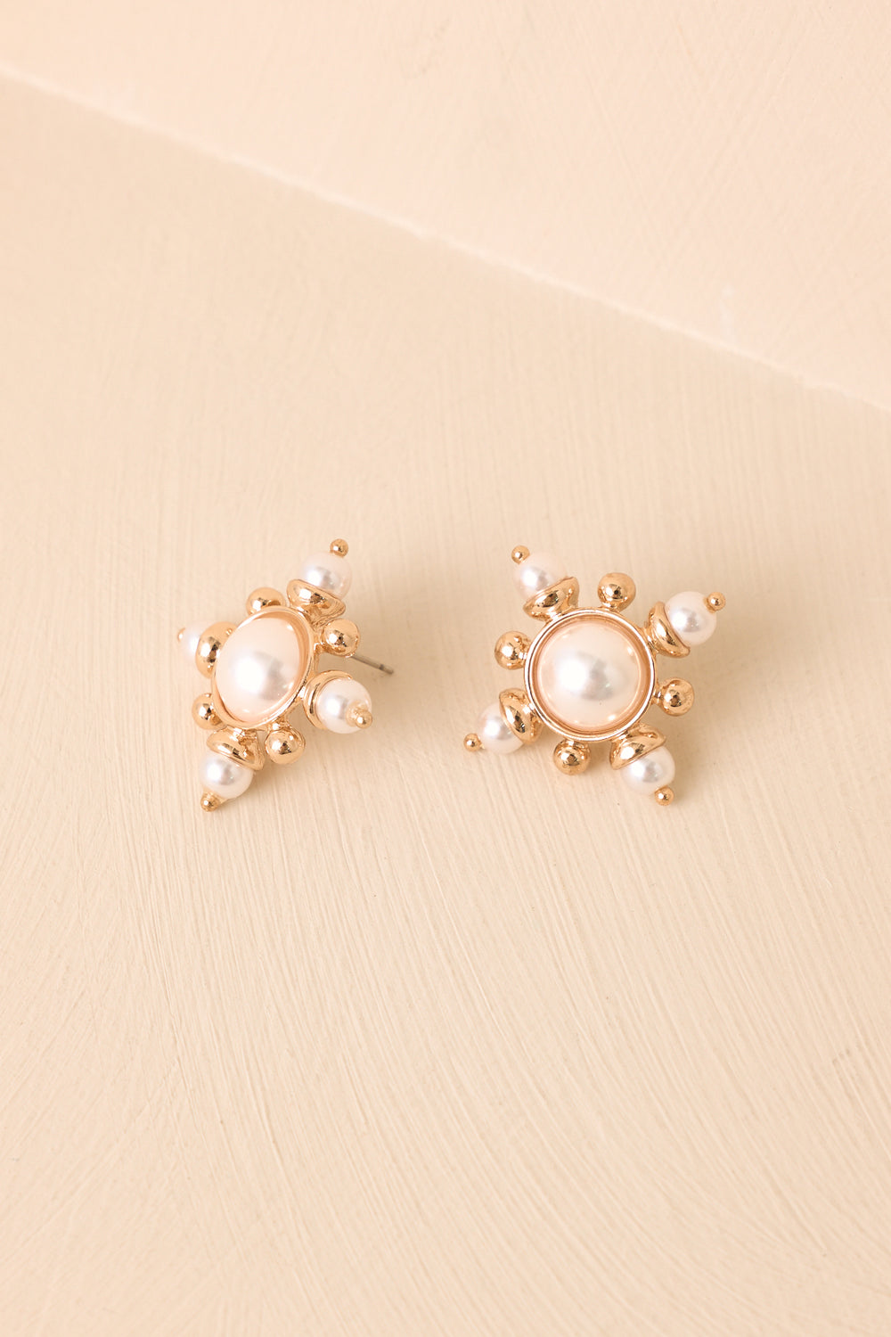Pearl-Starburst-Earrings-Displayed-Against-Beige-Background-With-Gold-Accents
